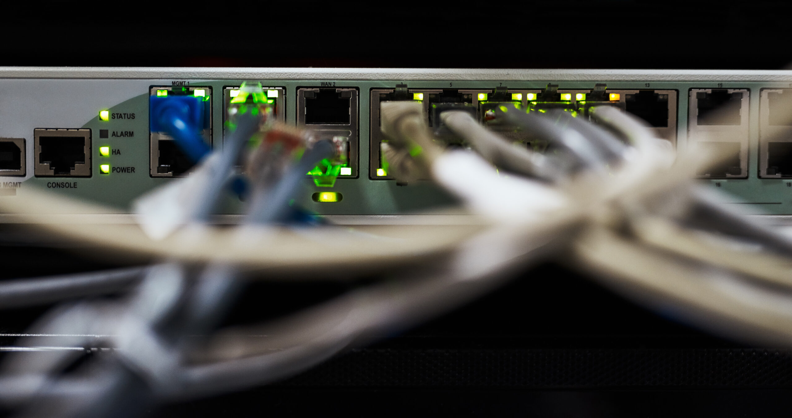 Nahaufnahme eines Data-Center-Switches mit mehreren angeschlossenen Netzwerkkabeln und leuchtenden Status-LEDs, symbolisiert IT-Infrastruktur und Netzwerklösungen der dierckgroup.