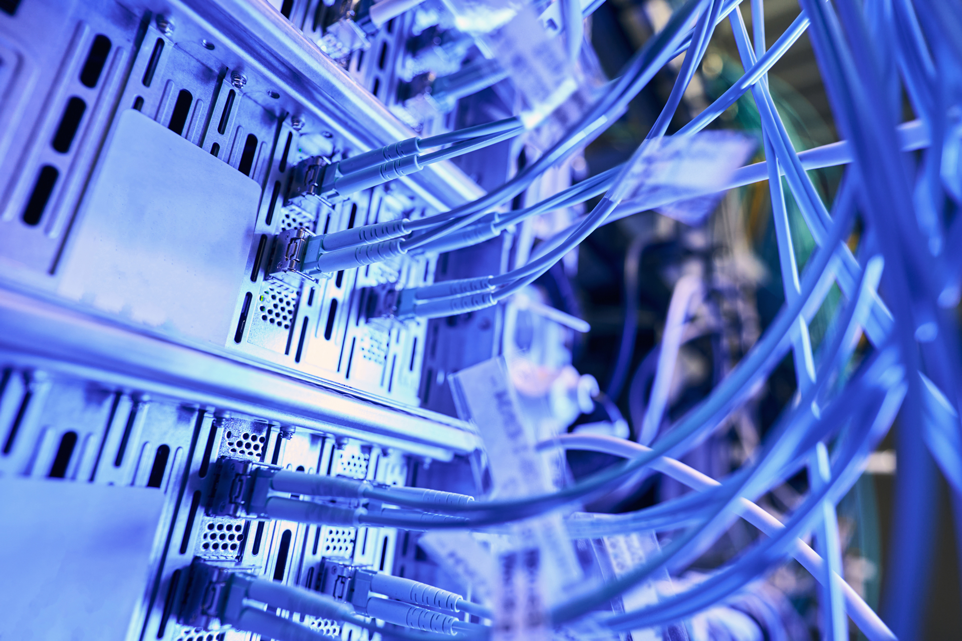Mehrere blaue Netzwerkkabel sind an die Rückseite eines Servers angeschlossen, der in einem Rechenzentrum steht. Die Kabel sind mit Etiketten versehen und verbinden den Server mit einem Server-Hub, was typische Netzwerklösungen und IT-Infrastruktur symbolisiert. Das Bild steht im Kontext von IT Solutions, Managed Services, Cloud Services und IT-Support der dierckgroup.