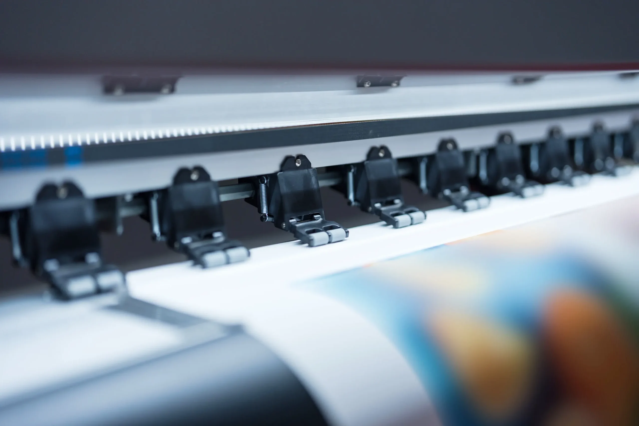 Nahaufnahme von Druckköpfen eines Großformatdruckers, der farbige Bilder auf Papier druckt, symbolisiert moderne Scan and Printing Lösungen im Bereich Digitalisierung und IT-Systemhaus.