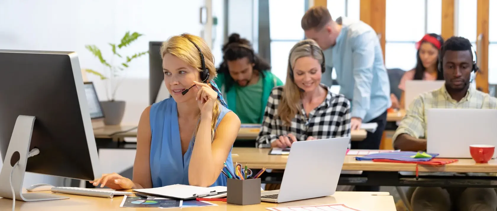 Mehrere Mitarbeitende in einem modernen Büro mit Headsets und Laptops, die Kundenservice und IT-Support leisten, symbolisieren professionelle IT-Beratung und Managed Services der dierckgroup.